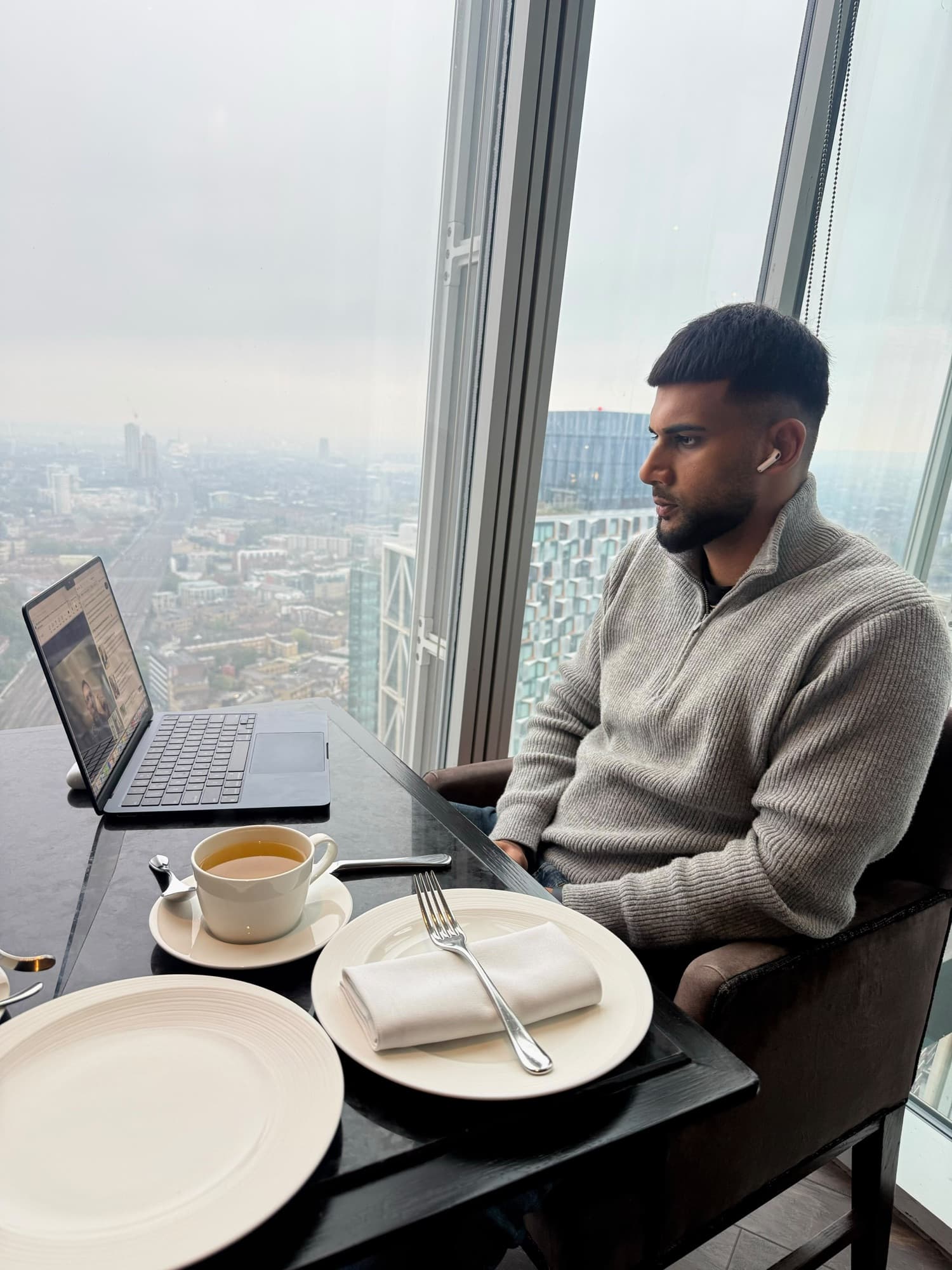 Niral on a video session with a client, laptop open beside a window overlooking London
